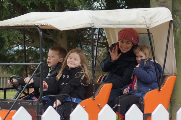 Jonge gezin op een oranje auto fairgound rit — Stockfoto