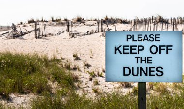 Ateş Adası deniz fenerine giden yolda kırık çitleri olan kum tepelerinin önündeki kumullardan uzak durun..