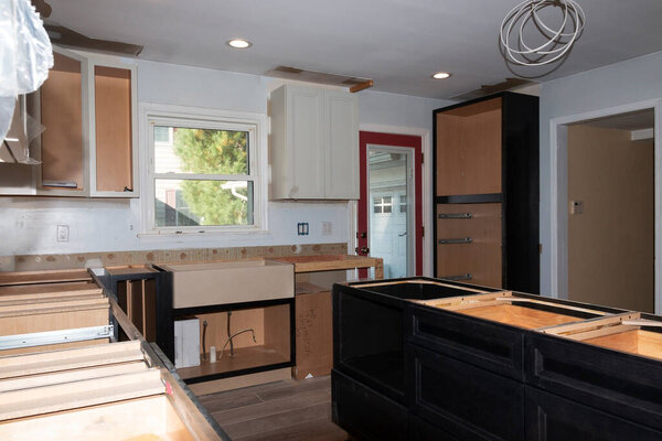 A residential kitchen home improvement project with new cabinets, flooring, sink and appliances being installed.