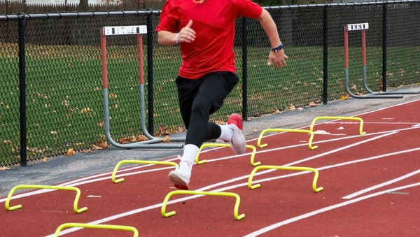 High School Track Runner Kører Små Gule Mini Hurdels Track - Stock-foto