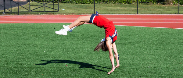 Школьная чирлидерша из хиф-хоп-хоп школы перевернута вверх дном, когда она практикуется в беге, спотыкаясь на поле..