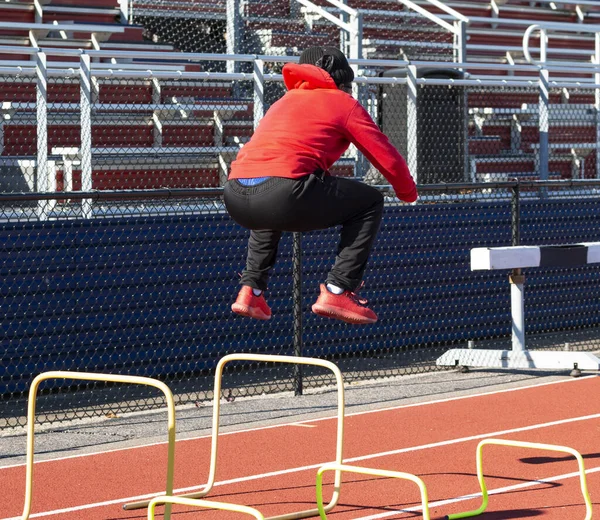 Visão Traseira Atleta Ensino Médio Pulando Alto Sobre Barreiras Amarelas — Fotografia de Stock