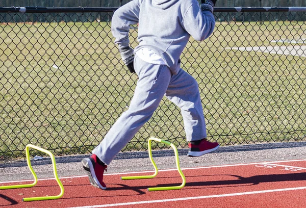 High School Runner Wearing Gray Sweatsuit Running Yellow Mini Hurdles — стоковое фото