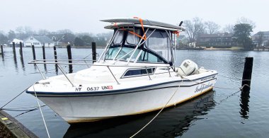 Babylon, New York, USA - 2 January 2022: A motor boat properly named the Independence with empy slips all around it and surfboards tied to the top.