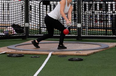 High school girl throwing the wieght during an indoor track and field competition.