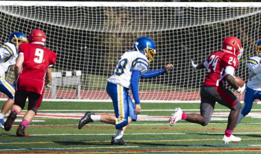 Sahadaki bir lise futbol maçında defans takibi ve koşucu savunması.