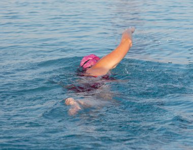Sabahın erken saatlerinde havuzda tek başına yüzen bir kadının arka görüntüsü..