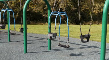 Mavi ve yeşil bir salıncak, üzerinde çocuğunuzu sallayacak bir salıncak olan bir parkta lastik güvenli bir yüzey..