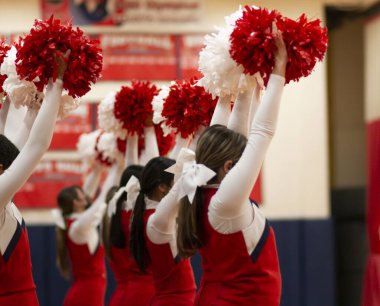 Ponponlarını havada tutan ponpon kızlar basketbol maçında kenarda tezahürat yapıyorlar..