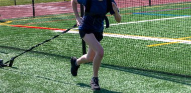 Liseli bir kız yeşil bir çim tarlasında kızak sürüyor balkon koruyucusunun yanında değil..