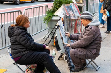 New York City, New York, ABD - 21 Kasım 2021: Central Park 'ın dışındaki kaldırımda oturan bir kadın ressam portresi çiziyor.