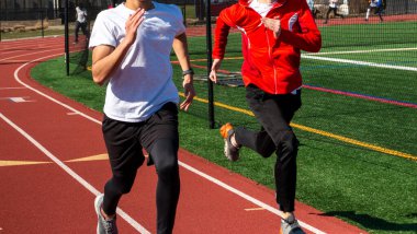 Liseli çocuklar kırmızı pistte ikili koşuyor..