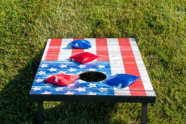 在美国国旗上挂着红包和蓝包的玉米孔游戏的近景 — 图库照片