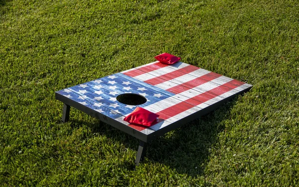 两个红豆袋在玉米孔游戏上 在绿色的草地上被描绘成美国国旗 — 图库照片