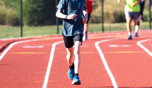 Lisede koşu pistinde koşan koşucuların ön görünümü.