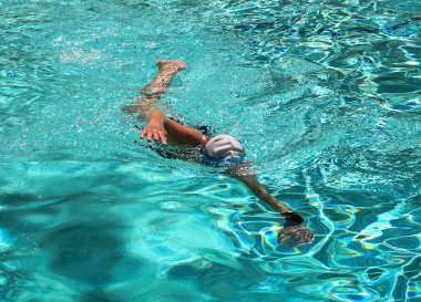 Front view of a women wearing a bathing cap swimming lapsin a hotel pool.