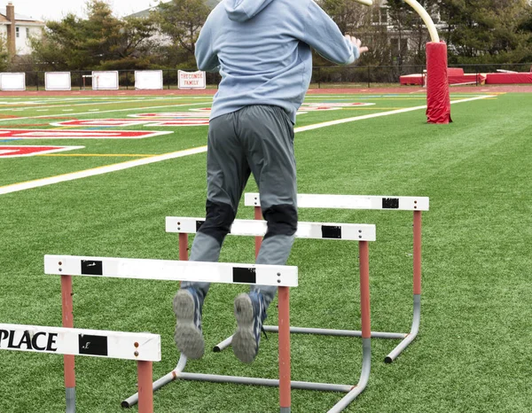Rear View High School Boy Jumping Track Hurdles Turf Field — Stok fotoğraf