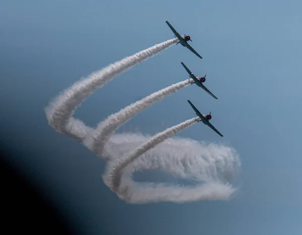 Three of the  Skytypers acrobatic airplane performance team perfoming at the Jones Beach Air Show leaving a long smoke trail.
