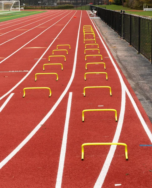 Two track lanes set up with yellow mini hurdles for runners to perform the wicket drill over at practice.