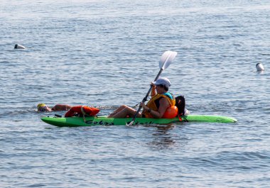 Brightwaters, New York, USA - 14 July 2022: A female in a kayak protecting a female swimming in the open waters of the Great South Bay during the Maggie Fischer Swim across the bay fundraiser.