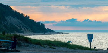 Sunset making an orange and red sky between the clouds over the hills and water of Sunken Meadow State Park on a mid August evening in 2021.