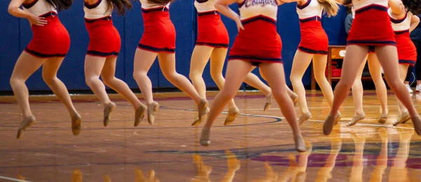 High school kickline team dancing at half time of a basketball game.