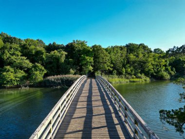 Overhead view of the wood bridge at Sunken Meadow State Park looking toward the picnin area with a blue sky taken with a drone.