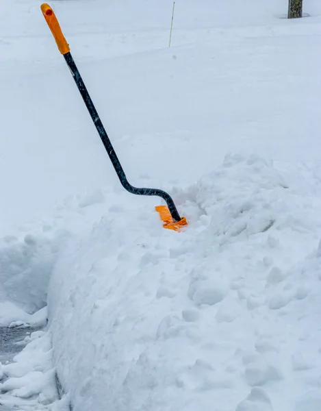 雪の嵐の後に雪の銀行に衝突した雪のシャベルは シャベルにどれだけの雪があるかを示しています — ストック写真