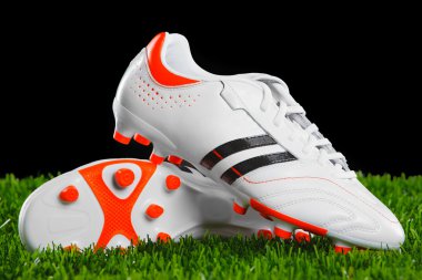 Soccer shoes on the green grass. clipart