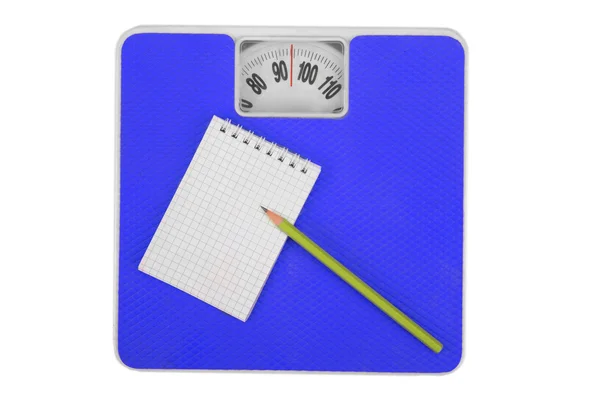 Scales and notebook with a pencil. — Stock Photo, Image