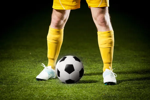 Pallone da calcio e piedi di un giocatore di calcio Immagine Stock
