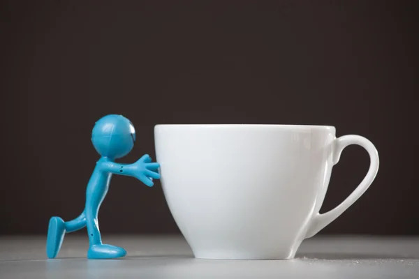 Homem azul empurrando e xícara de café . — Fotografia de Stock