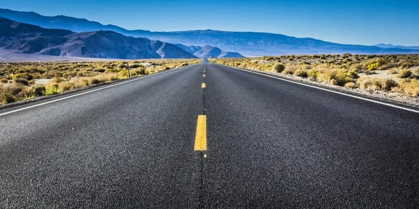 Woestijn snelweg met bergen in de achtergrond — Stockfoto