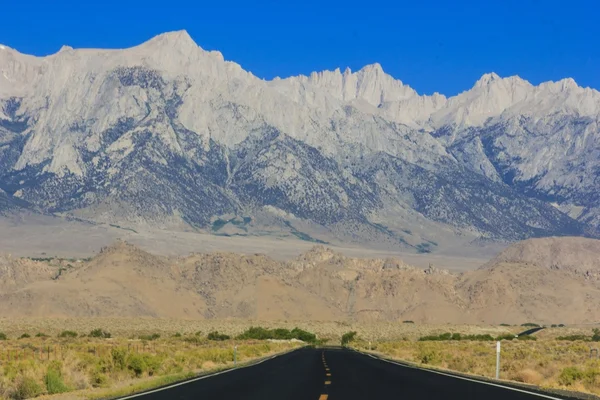 Desert highway med bergen i bakgrunden — Stockfoto