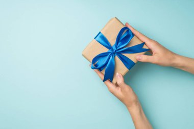 El sanatları el sanatları hediye kutusu veren ilk kişi görüntüsü canlı mavi kurdele ile izole edilmiş pastel mavi arka plan boş alan