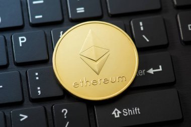 Siyah klavye arka planında ethereum sembolü olan altın paranın yakın plan fotoğrafı.