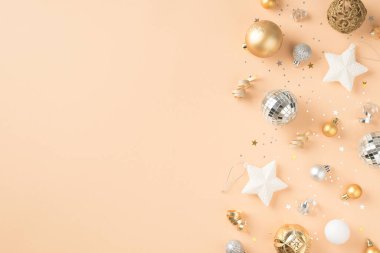 Beyaz altın ve gümüş noel ağacı süslemelerinin en üst görüntüsü yıldızlar disko topları pulları ve izole edilmiş bej arka planda boş alan ile yılan balığı.