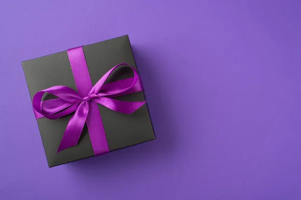 上图为黑色礼品盒 用彩带包裹 在紫罗兰色背景上的弓形图案 — 图库照片