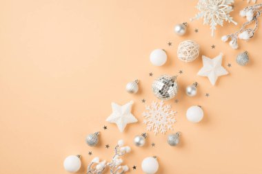 Beyaz ve gümüş noel ağacı süslemelerinin en üstteki fotoğrafı disko topları kar taneleri ve kopyalanmış bej arkaplanlı konfeti.