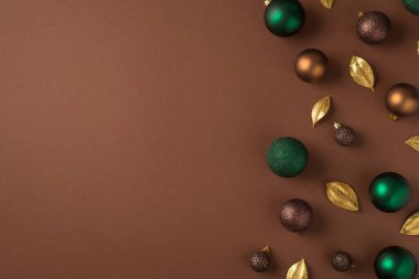 Noel ağacı süslemelerinin en üst görüntüsü yeşil kahverengi altın toplar ve tenha kahverengi arka planda boş alan ile altın yapraklar.