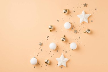 Sıra kompozisyonu beyaz ve altın noel ağacı süslemeleri küçük toplar parlak yıldızlar ve izole edilmiş bej arkaplan üzerinde konfeti boş alan