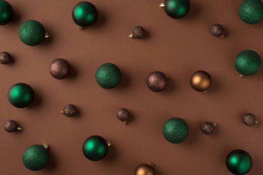 Yeşil kahverengi ve altın noel ağacı toplarının izole edilmiş kahverengi arka planda en üstteki fotoğrafı.