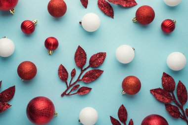 Beyaz ve kırmızı noel ağacı süslemelerinin en üstteki fotoğrafı izole edilmiş pastel mavi arka planda toplar ve dallar