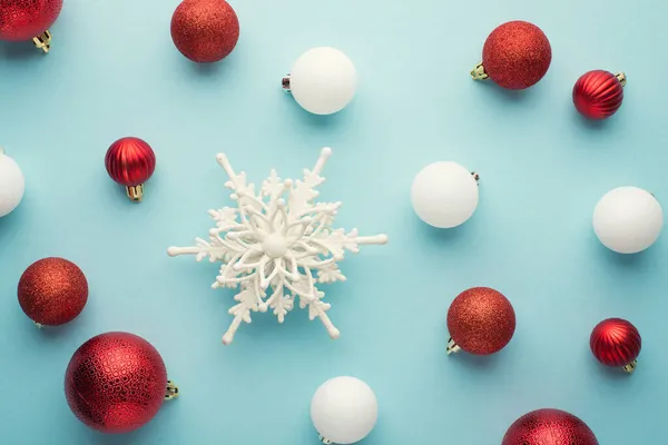 白色和红色圣诞树装饰球和雪花在孤立的淡蓝色背景上的俯瞰照片 — 图库照片