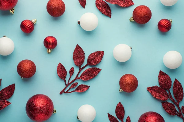 白色和红色的圣诞树装饰球和树枝在孤立的淡蓝色背景上的俯瞰照片 — 图库照片