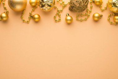 Altın noel ağacı toplarının ve sakallı çelengin izole edilmiş bej arka planda boş alanla en üstteki fotoğrafı.