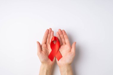 Avuç içlerinde kırmızı kurdele tutan el fotoğraflarının olduğu ilk kişi beyaz arka planda izole edilmiş ve kopyalama alanı olan AIDS 'in sembolü.