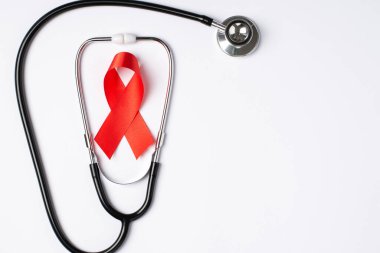 Stetoskop ve AİDS 'in kırmızı ipek kurdele sembolünün üst görünümü boş arkaplan ile izole edilmiş beyaz arkaplan üzerinde farkındalık