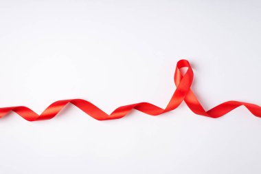 Ayırt edilmiş beyaz arkaplan üzerindeki AIDS farkındalığının kıvrımlı kırmızı ipek kurdele sembolünün üst görünüm fotoğrafı