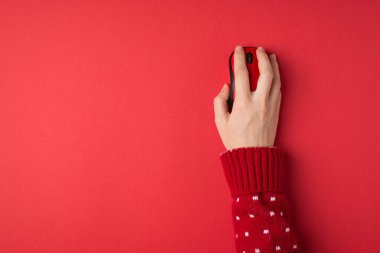 Kırmızı ve beyaz süveterli bir kadının, izole edilmiş kırmızı arka planda kablosuz fareyle çekilmiş ilk resmi.